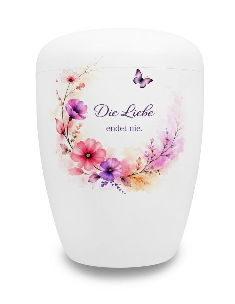 Weiße Urne mit Spruch "Die Liebe endet nie" in einem floralen Blütenring